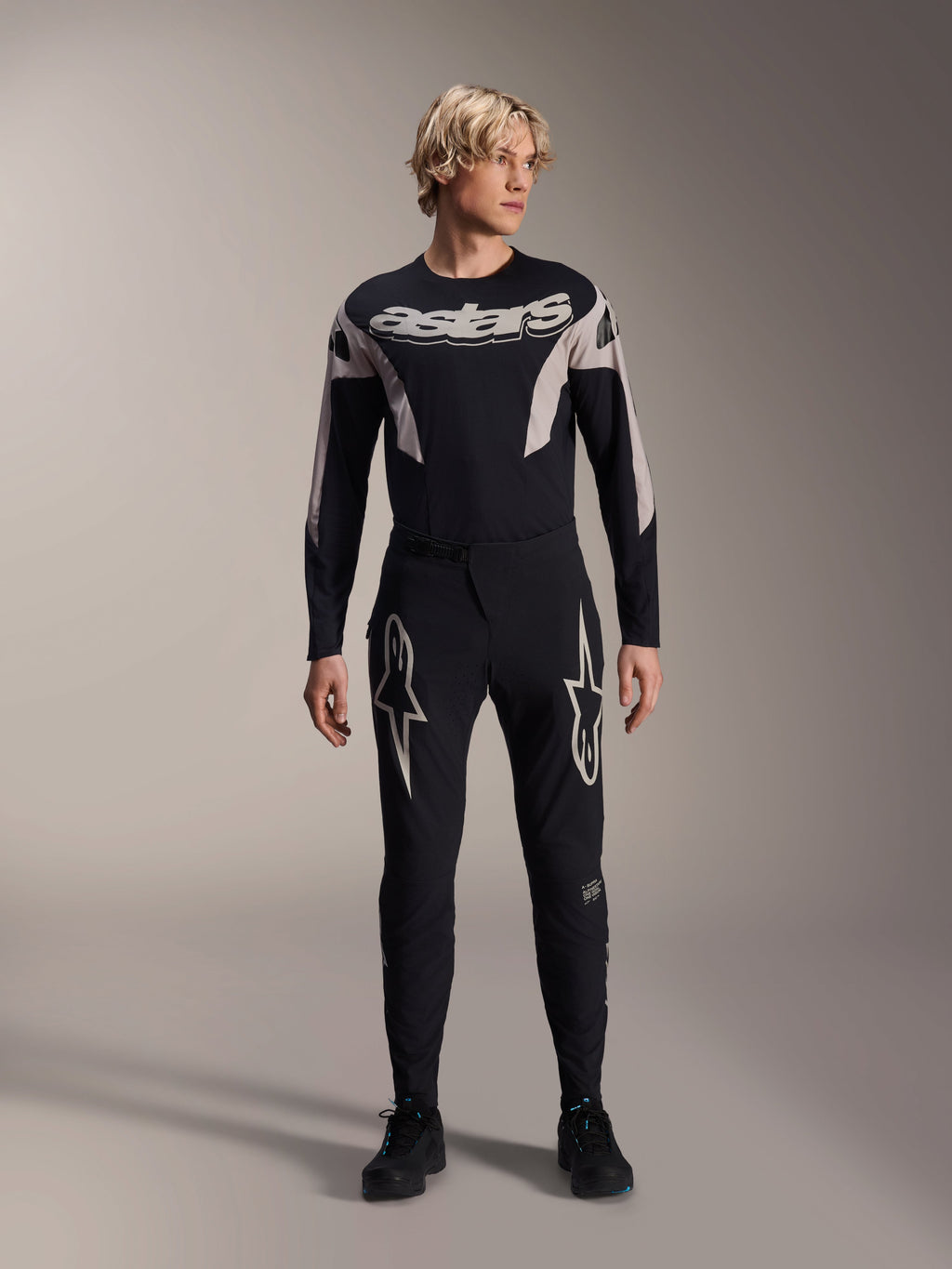 Alpinestars A-Supra Melt Hose und passendes langärmliges Trikot, Modell trägt schwarze MTB-Ausrüstung mit großen weißen Sterngrafiken auf den Oberschenkeln und „astars“-Branding auf der Brust, professionelle Mountainbike-Rennbekleidung