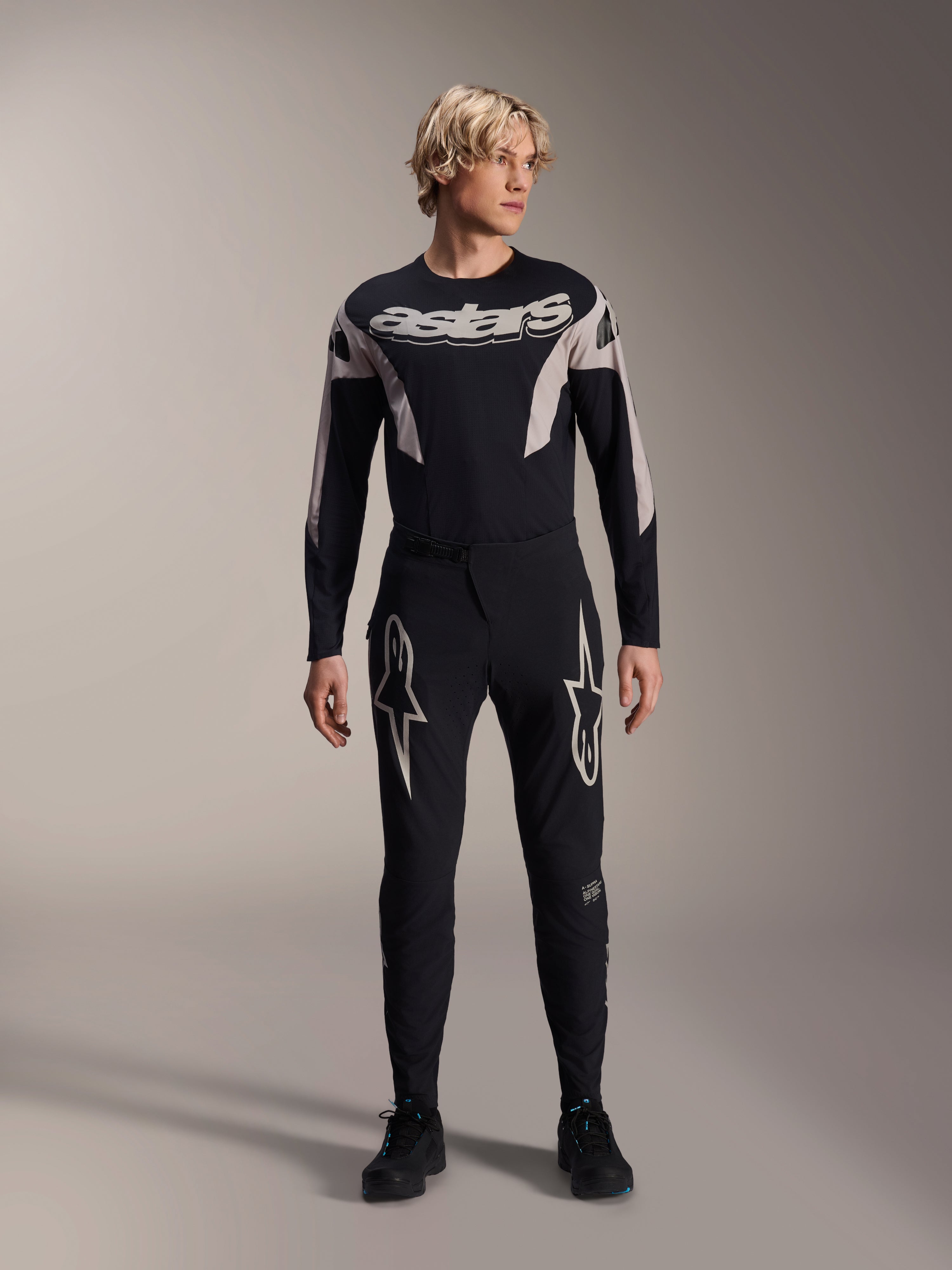 Alpinestars A-Supra Melt Hose und passendes langärmliges Trikot, Modell trägt schwarze MTB-Ausrüstung mit großen weißen Sterngrafiken auf den Oberschenkeln und „astars“-Branding auf der Brust, professionelle Mountainbike-Rennbekleidung