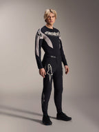 Männliches Model trägt das Alpinestars A-Supra Melt Jersey – Langarm, Schwarz mit grauen Grafikakzenten, 'astars'-Brustlogo, kombiniert mit passender schwarzer Hose und Schuhen, Performance-Mountainbike-Ausrüstung für Offroad-Rennen