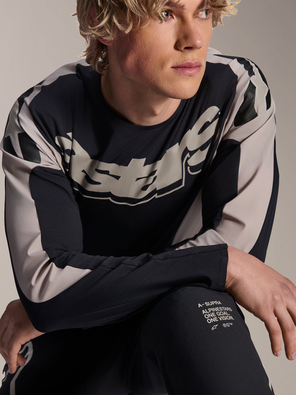Alpinestars A-Supra Melt Trikot, Langarm-MTB-Trikot, Schwarz mit hellgrauen Grafiken, von einem Model getragen, mit auffälligem Brust-Logo und „One Goal. One Vision.“-Branding, Performance-Mountainbike-Bekleidung