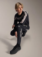 Alpinestars A-Supra Melt Hose und Langarmtrikot, Schwarz und Grau, mit auffälligem weißem Branding und Stern-Logos, getragen von einem männlichen Model in hockender Pose, abgestimmte MTB-Rennausrüstung
