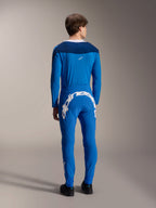 Männliches Modell von hinten gesehen im Alpinestars A-Supra Melt Langarm-Trikot in Blau, kombiniert mit passender blauer Performance-Hose mit großem weißem Alpinestars-Schriftzug auf der Rückseite, komplette MTB-Rennausrüstung.
