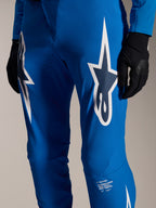 Alpinestars A-Supra Melt Hose, Blaue Radhose, mit großen weißen Astars-Logos auf den Oberschenkeln, lasergeschnittenen Perforationen für Belüftung und charakteristischem Branding am Unterschenkel, getragen mit schwarzen Handschuhen, Performance-MTB-Ausrüstung