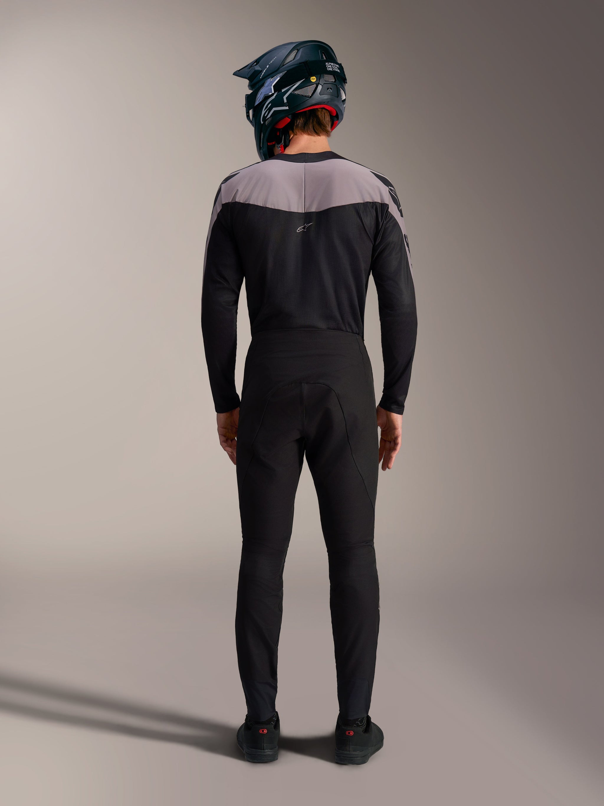Alpinestars A-Supra Elite MTB kit in black, featuring performance pants and jersey with a full-face helmet, back view.