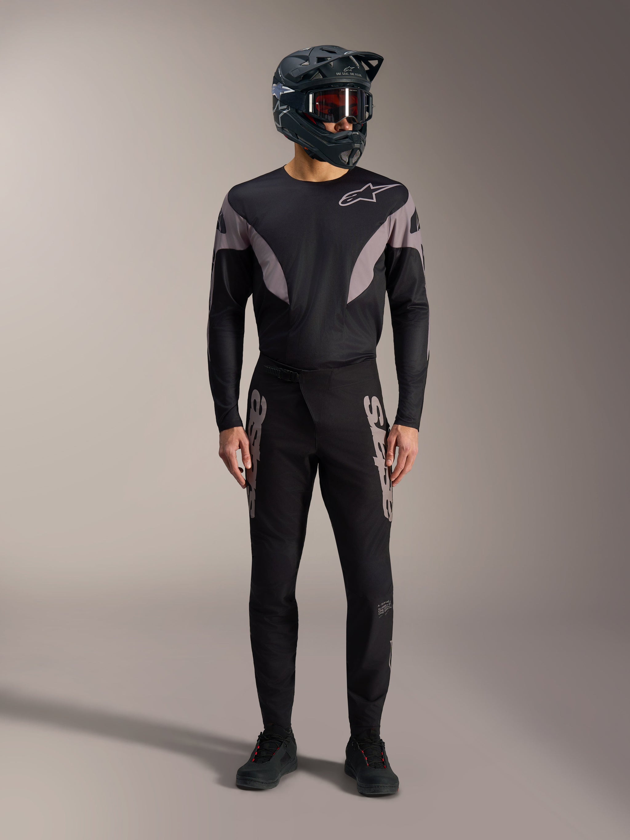 Black A-Supra Elite MTB kit featuring a long-sleeve jersey and racing pants with grey logos and a full-face helmet.