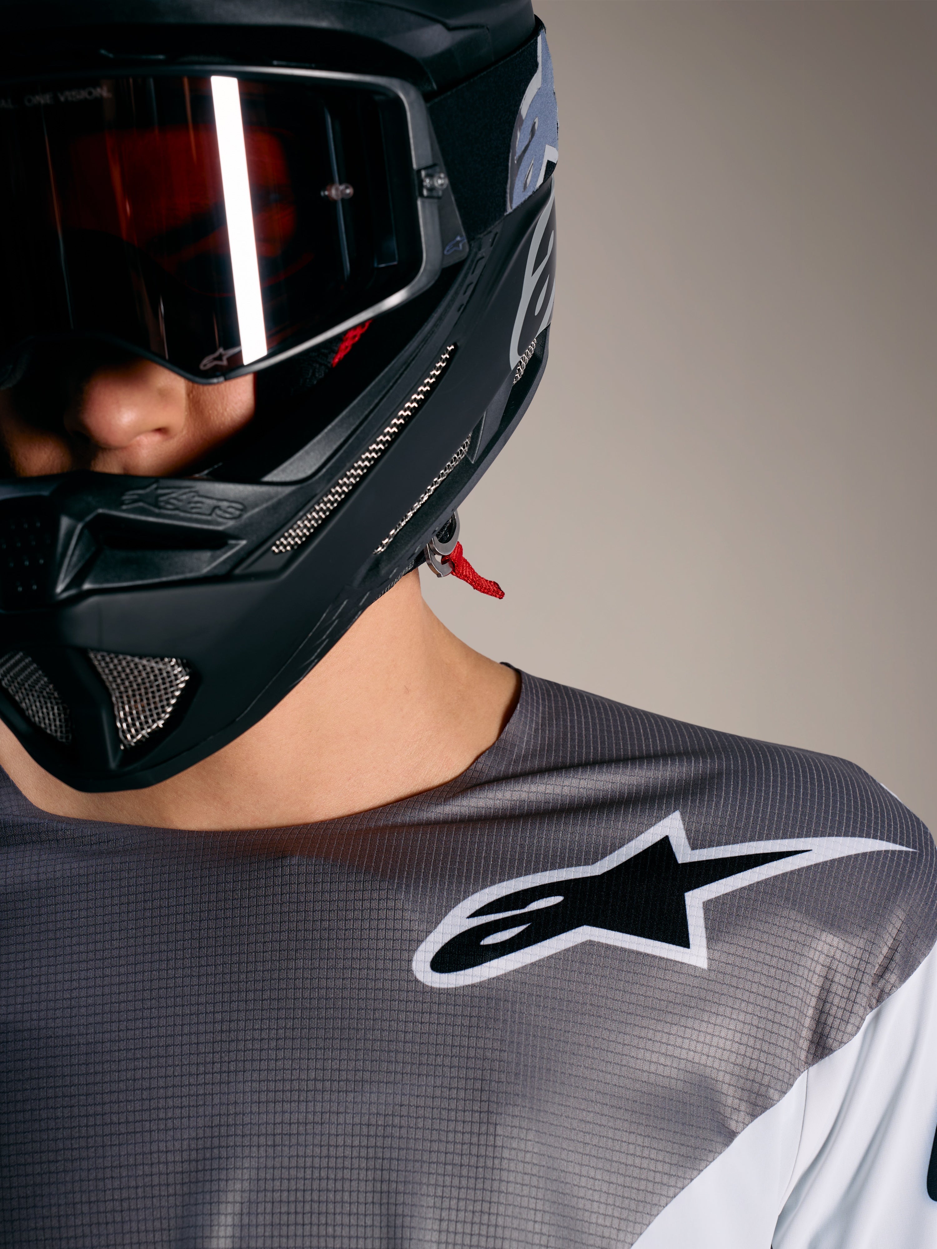 Alpinestars A-Supra Elite Trikot in Faded Gray mit weißem Logo, mikroperforiertem Stoff und schwarzem MTB-Helm.