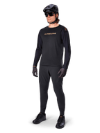 Alpinestars A-Aria Polartec Switch Long Sleeve Jersey, Black, bronze branding on chest, worn by mountain biker with black helmet and sunglasses, performance cycling apparel for trail riding