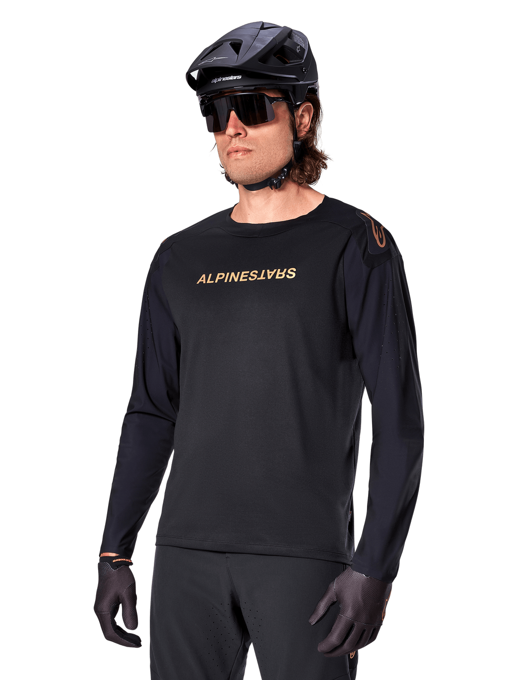 Alpinestars A-Aria Polartec Switch Long Sleeve Jersey, Black with gold logo, MTB mountain biking apparel, worn with a black helmet and sunglasses, featuring laser-cut ventilation on the sleeves and moisture-wicking Polartec fabric for off-road performance