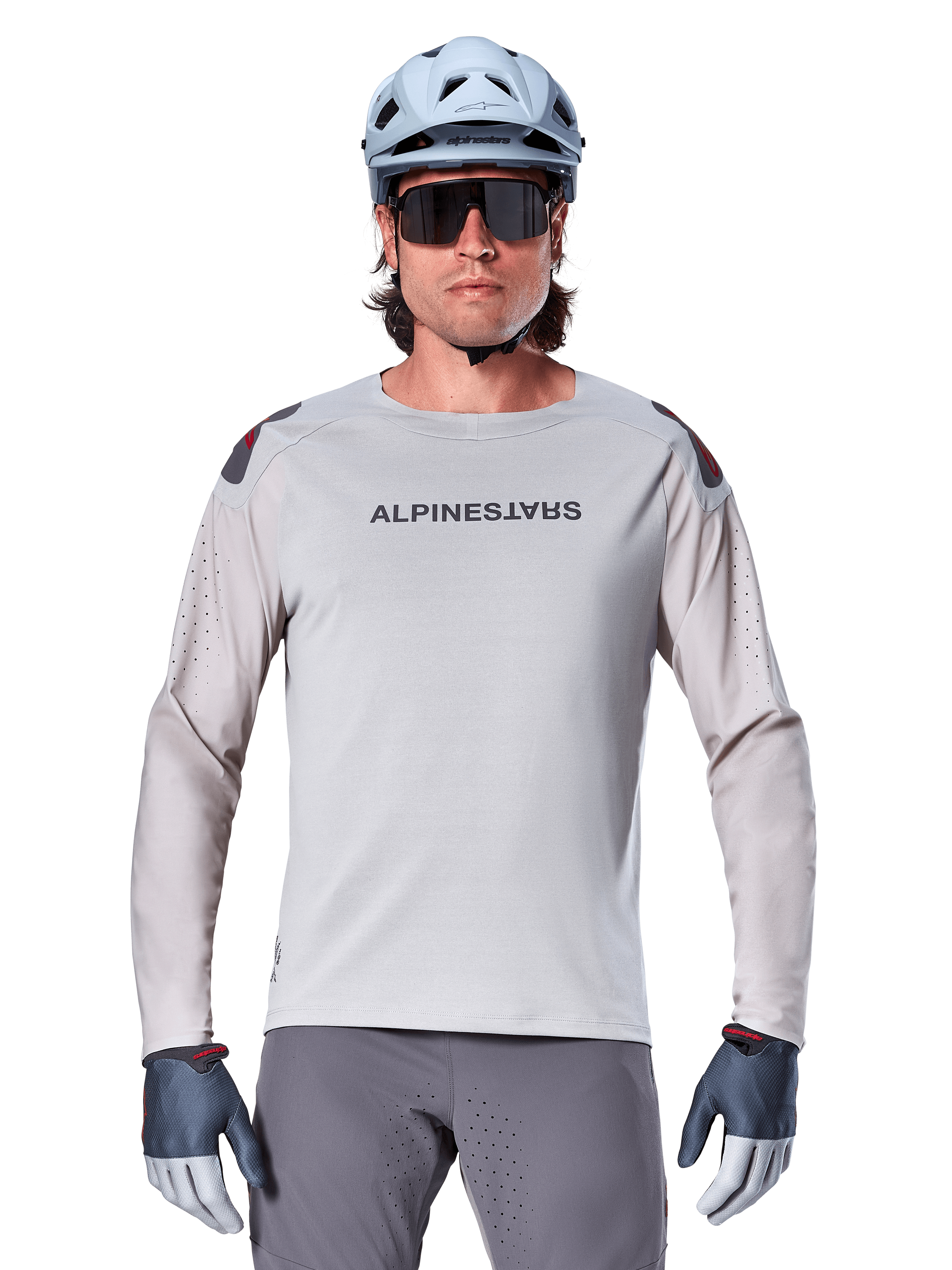 Alpinestars A-Aria Polartec Switch Long Sleeve Jersey, Light Gray mountain bike jersey featuring laser perforations on sleeves and chest branding, worn with light blue helmet, sunglasses, and gray gloves