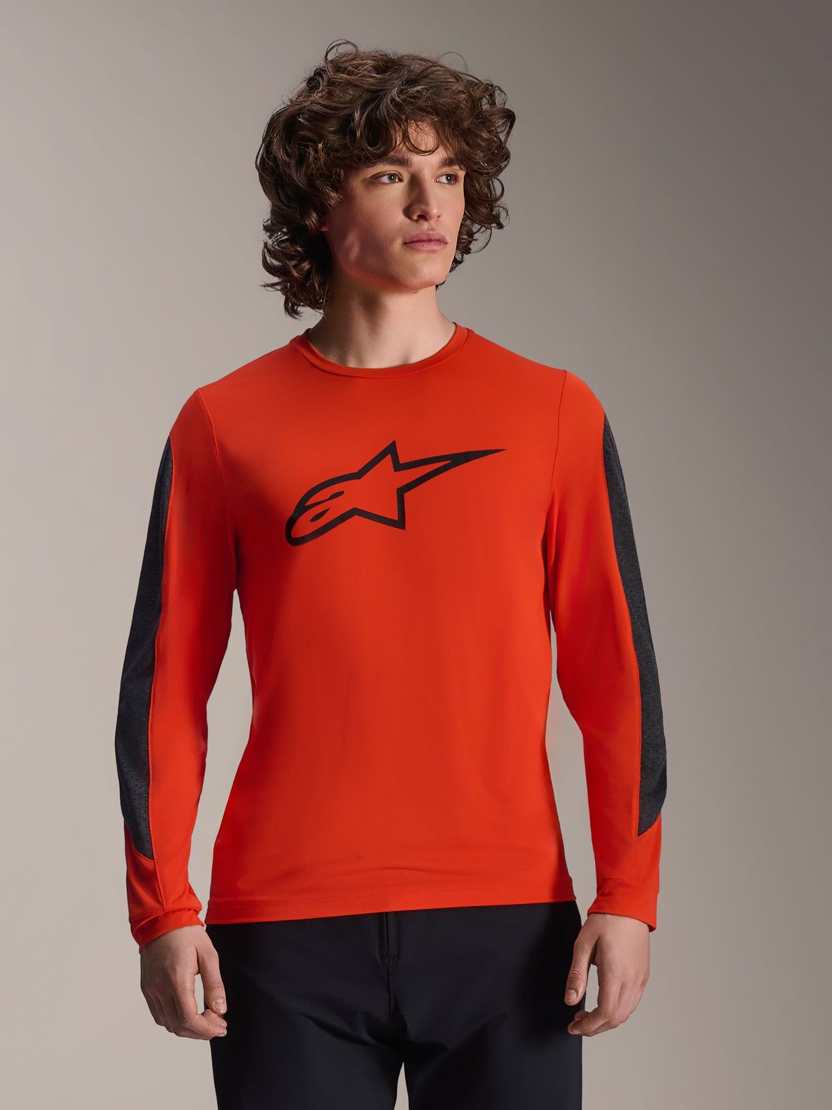 Alpinestars A-Dura Insert Astar Langarmtrikot, MTB-Trikot, Spicy Orange mit schwarzem Astar-Logo, dunkelgraue strapazierfähige Ärmeleinsätze, getragen von einem männlichen Model, Performance MTB-Radsportbekleidung