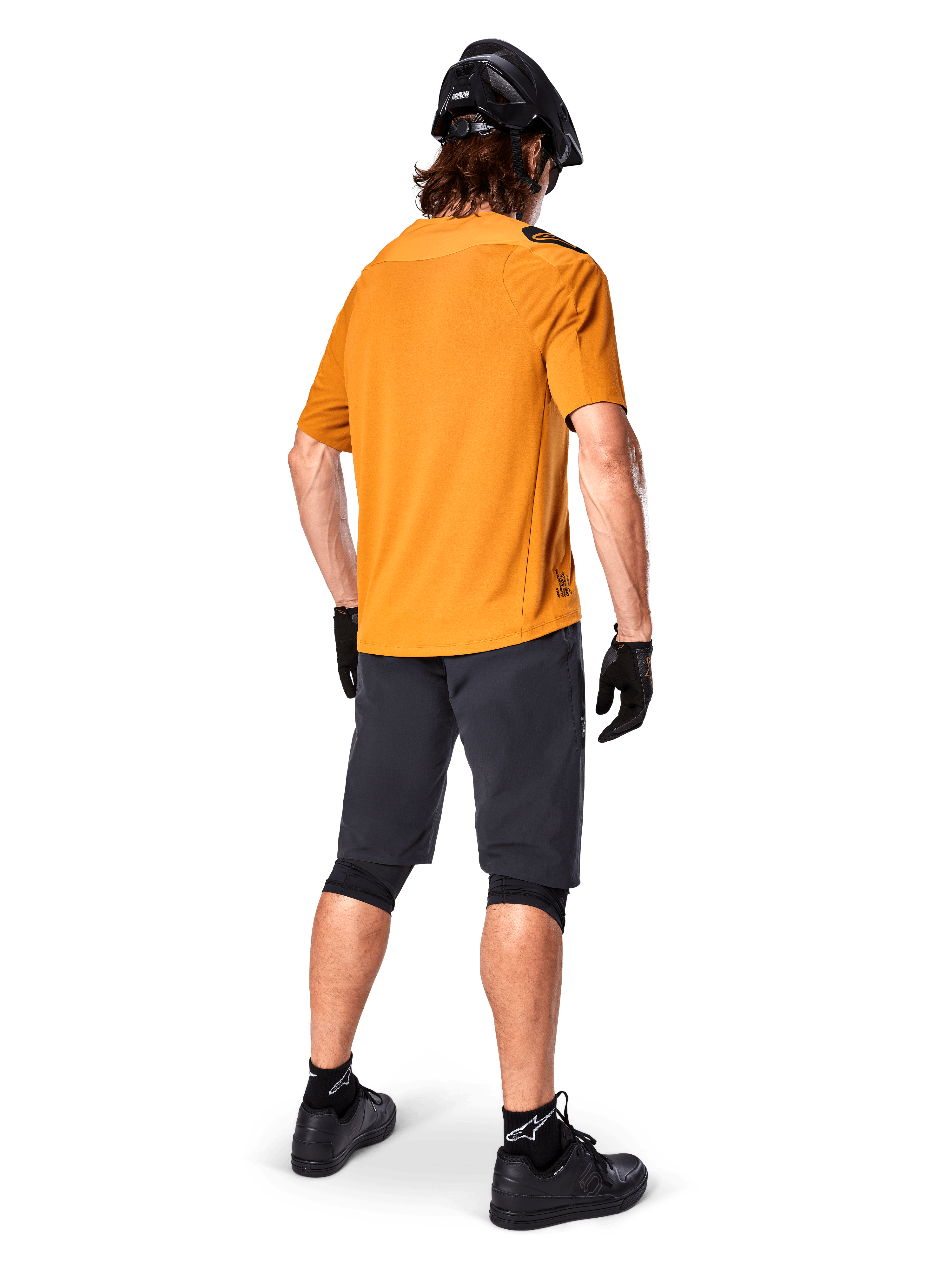 Alpinestars A-Aria Polartec Switch Trikot, kurzärmeliges MTB-Trikot, Dunkelgold, Rückansicht eines Models in dunkelgrauen Mountainbike-Shorts, schwarzem Helm und Handschuhen, technische Radsportbekleidung für Offroad-Trails