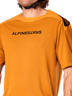 Alpinestars A-Aria Polartec Switch Jersey, kurzärmeliges MTB-Trikot, Dunkelgold, mit gespiegeltem schwarzem Alpinestars-Logo auf der Brust, technisches Funktionsgewebe für Mountainbike-Trailfahrten