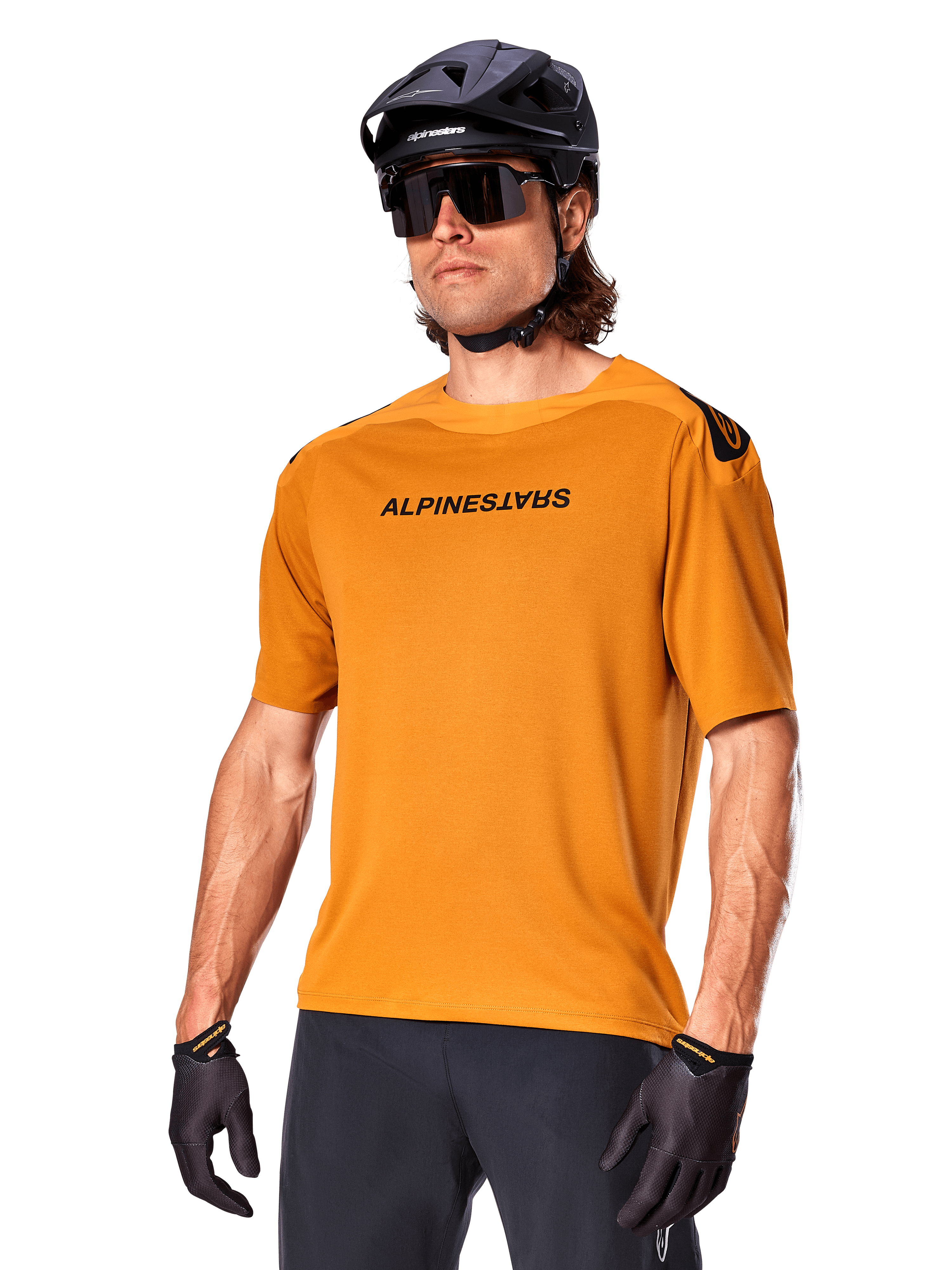 Alpinestars A-Aria Polartec Switch Trikot, Kurzarm-MTB-Trikot, Dunkelgold mit schwarzem Branding, getragen von Model mit schwarzem Helm, Sonnenbrille und Radhandschuhen, Hochleistungs-Mountainbike-Bekleidung