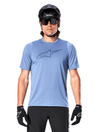 Männlicher Mountainbiker im Alpinestars A-Dura Dri Astar Kurzarmtrikot in Infinity Blue, mit dezentem Brustlogo und Mesh-Einsätzen, kombiniert mit einem schwarzen Helm, einer Sonnenbrille und schwarzen Handschuhen für ein technisches Radsport-Outfit