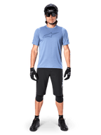 Männlicher Mountainbike-Fahrer im Alpinestars A-Dura Dri Astar Kurzarmtrikot in Infinity Blue, mit markantem Astars-Logo auf der Brust, kombiniert mit schwarzen MTB-Shorts, schwarzem Helm, Sonnenbrille und Schutzausrüstung für Geländefahrten