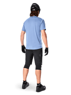 Alpinestars A-Dura Dri Astar Kurzarmtrikot, Infinity Blue, Rückansicht, kombiniert mit schwarzen Mountainbike-Shorts und Helm, technische Radsportbekleidung mit feuchtigkeitsableitendem Material und verlängertem Rückenteil