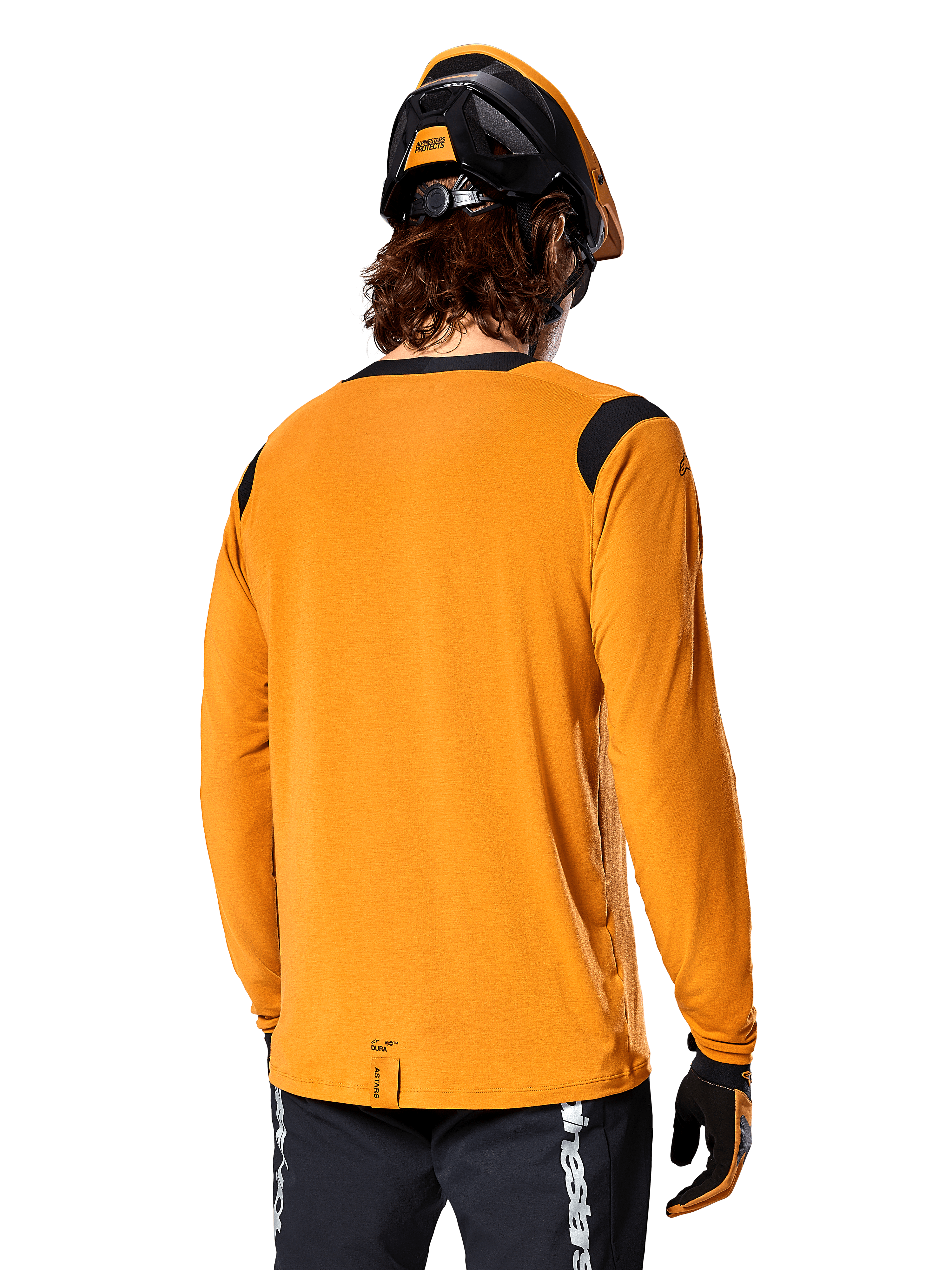 Alpinestars A-Dura Dri Wool Langarmtrikot in Dark Gold, Rückansicht eines Fahrers mit Mountainbike-Helm und Handschuhen, verfügt über schwarze Mesh-Einsätze an den Schultern und ein verlängertes Rückenteil, technische Radsportbekleidung für Trailfahrten