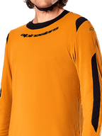 Alpinestars A-Dura Dri Wool Langarmtrikot, Dark Gold, Nahaufnahme des schwarzen Rundhalskragens mit Logo und schwarzen Mesh-Belüftungseinsätzen an den Schultern und Armen, Hochleistungs-Mountainbike-Bekleidung