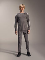 Alpinestars A-Dura Dri Wool Langarmtrikot, Dunkelgrau, getragen von einem Modell mit passender grauer Hose und schwarzen Schuhen, weißes Alpinestars-Branding auf der Brust, hellgraue Mesh-Einsätze an Schultern und Ärmeln, technische Mountainbike-Ausrüstung