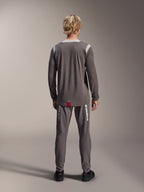 Alpinestars A-Dura Dri Wool Langarmtrikot, Dunkelgrau, Rückansicht am Modell, mit hellgrauen Mesh-Einsätzen an Schultern und Kragen, verlängerter Rückensaum mit kleinem roten Markenlabel, getragen mit passender grauer Radhose.