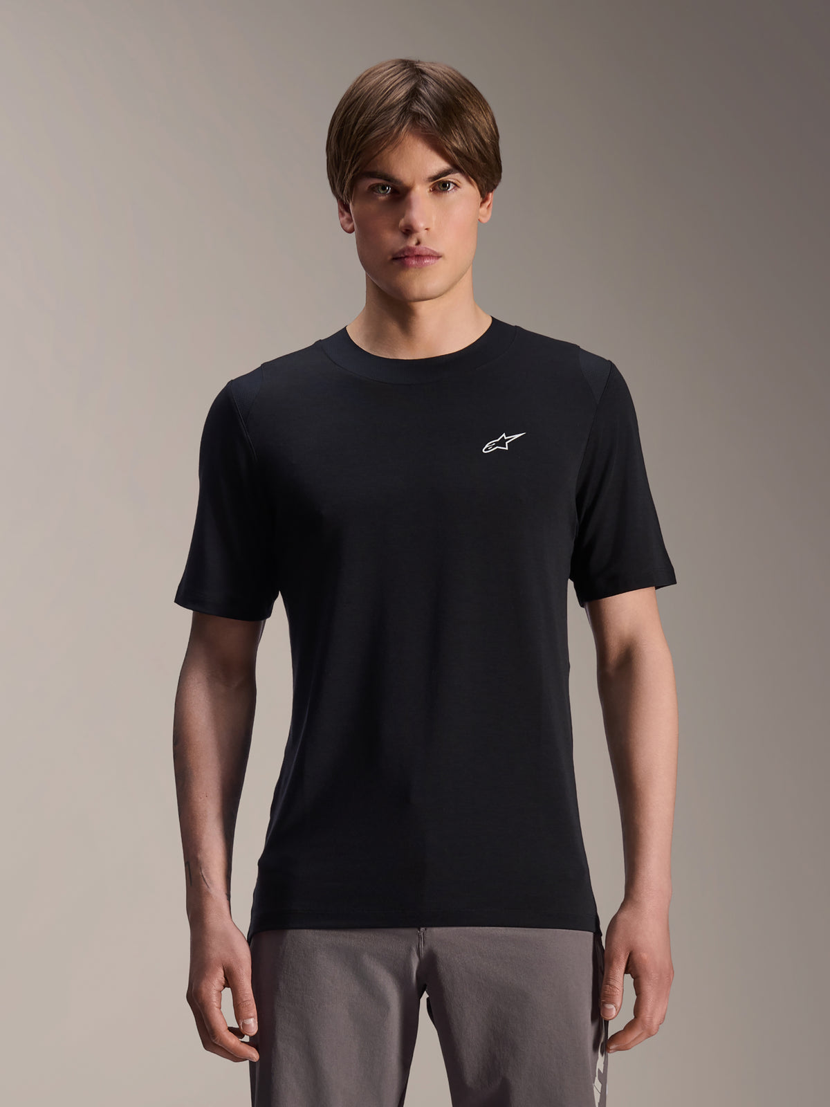 Alpinestars A-Dura Dri Wool Kurzarmtrikot, Schwarz, getragen von männlichem Model, kleines weißes Alpinestars-Logo auf der Brust, Performance-Radbekleidung für MTB-Trailfahrten, feuchtigkeitsableitendes drirelease-Wollgewebe