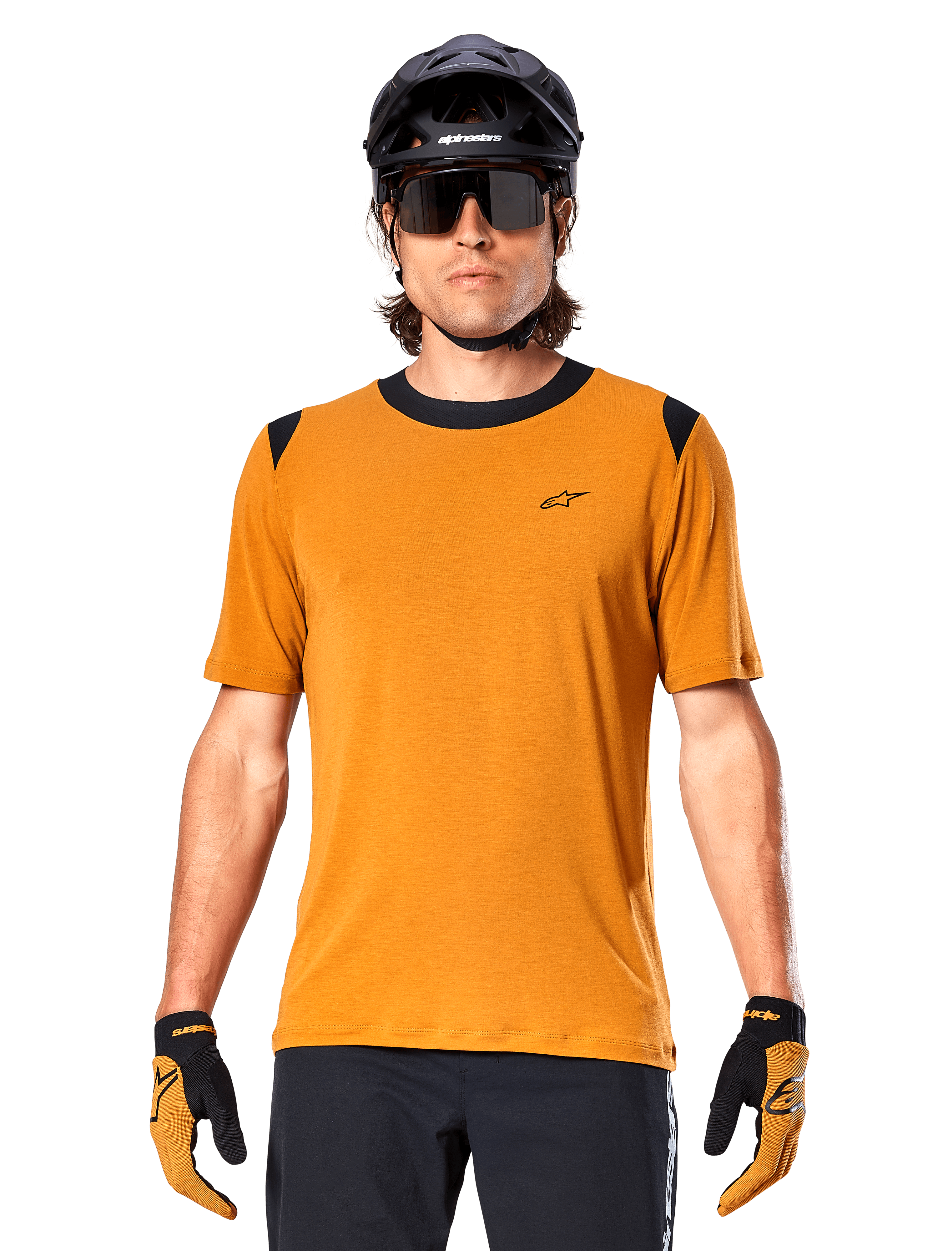 Alpinestars A-Dura Dri Wool Kurzarmtrikot, Dark Gold, getragen mit schwarzem MTB-Helm, Sonnenbrille und Handschuhen, mit schwarzem Kragen und Schultereinsätzen, atmungsaktives drirelease-Wollmischgewebe für Mountainbiking