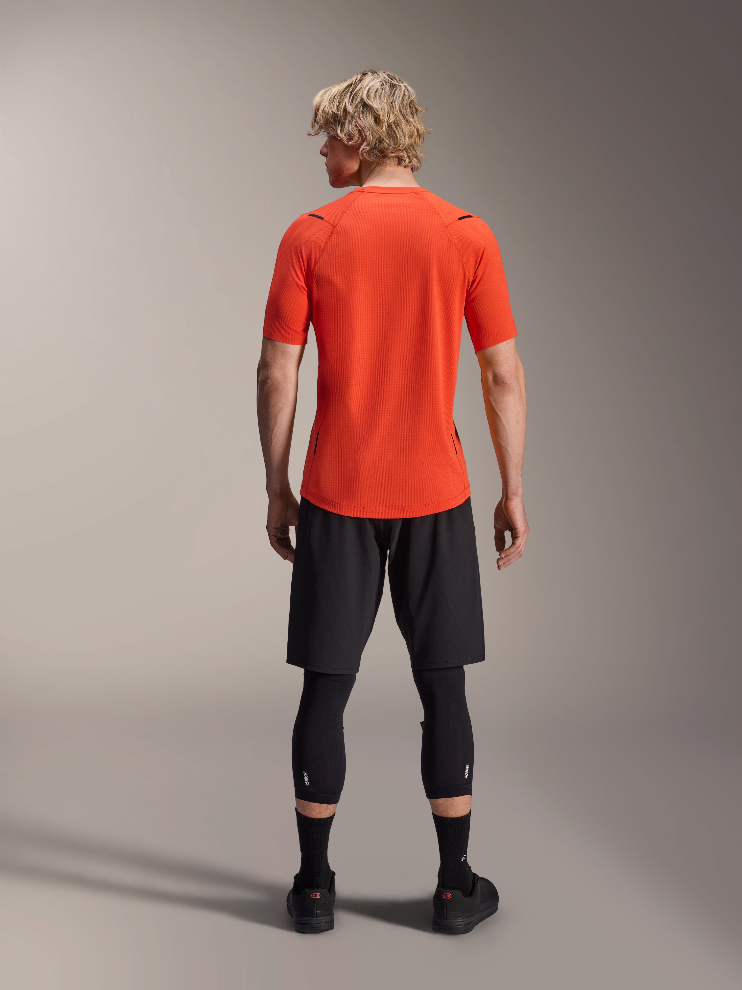 Alpinestars A-Aria Astar Trikot, Kurzarm-MTB-Trikot, Spicy Orange, Rückansicht mit Performance-Passform und längerem abfallendem Saum, kombiniert mit schwarzen Radshorts und Leggings