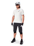 MTB-Fahrer trägt Alpinestars A-Aria Astar Kurzarmtrikot in White Dove, kombiniert mit schwarzen Mountainbike-Shorts, weißem Helm und schwarzen Knieschonern, mit kleinem schwarzen Logo auf der Brust, koordinierte Fahrradausrüstung für Trail-Performance