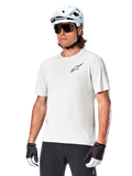 Alpinestars A-Aria Astar Kurzarmtrikot, White Dove, getragen von einem Radfahrer mit weißem Helm und dunkler Sonnenbrille, mit kleinem schwarzem Stern-Logo auf der Brust, atmungsaktive Performance-Ausrüstung für Mountainbiking
