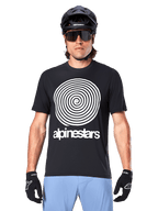 Alpinestars A-Dura Oscar Trikot, Kurzarm-MTB-Trikot, Schwarz, mit einer großen weißen Vintage-Oscar-Spiralgrafik auf der Brust, getragen mit einem schwarzen Fahrradhelm, Sonnenbrille, schwarzen Handschuhen und hellblauen Shorts, vom Heritage-Stil inspirierte Offroad-Fahrradausrüstung