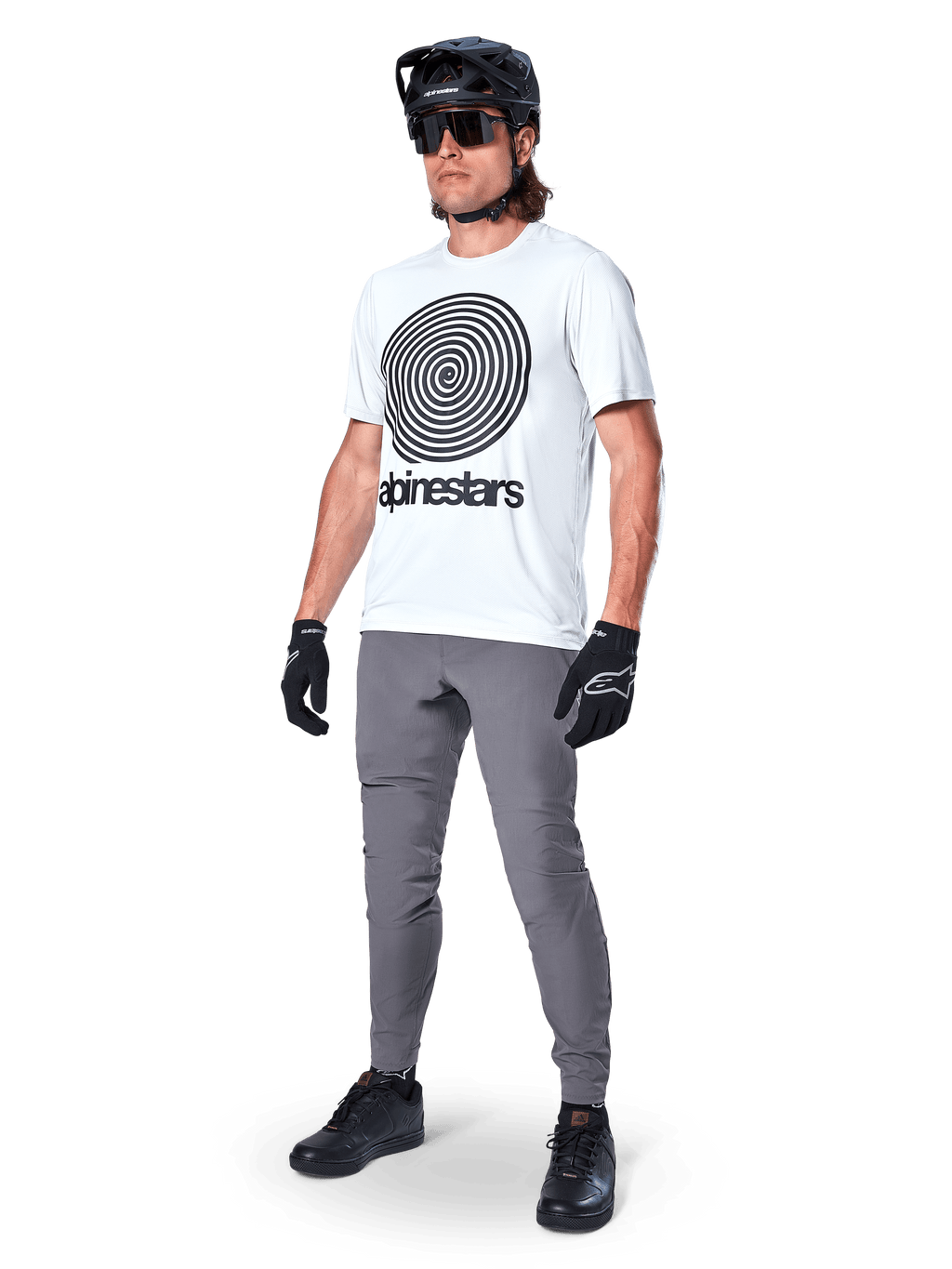 Alpinestars A-Dura Oscar Kurzarmtrikot, White Dove mit großer schwarzer Spiralgrafik, getragen von einem Fahrer mit grauer MTB-Hose, schwarzem Helm und Handschuhen, Performance-Radbekleidung für Geländefahrten