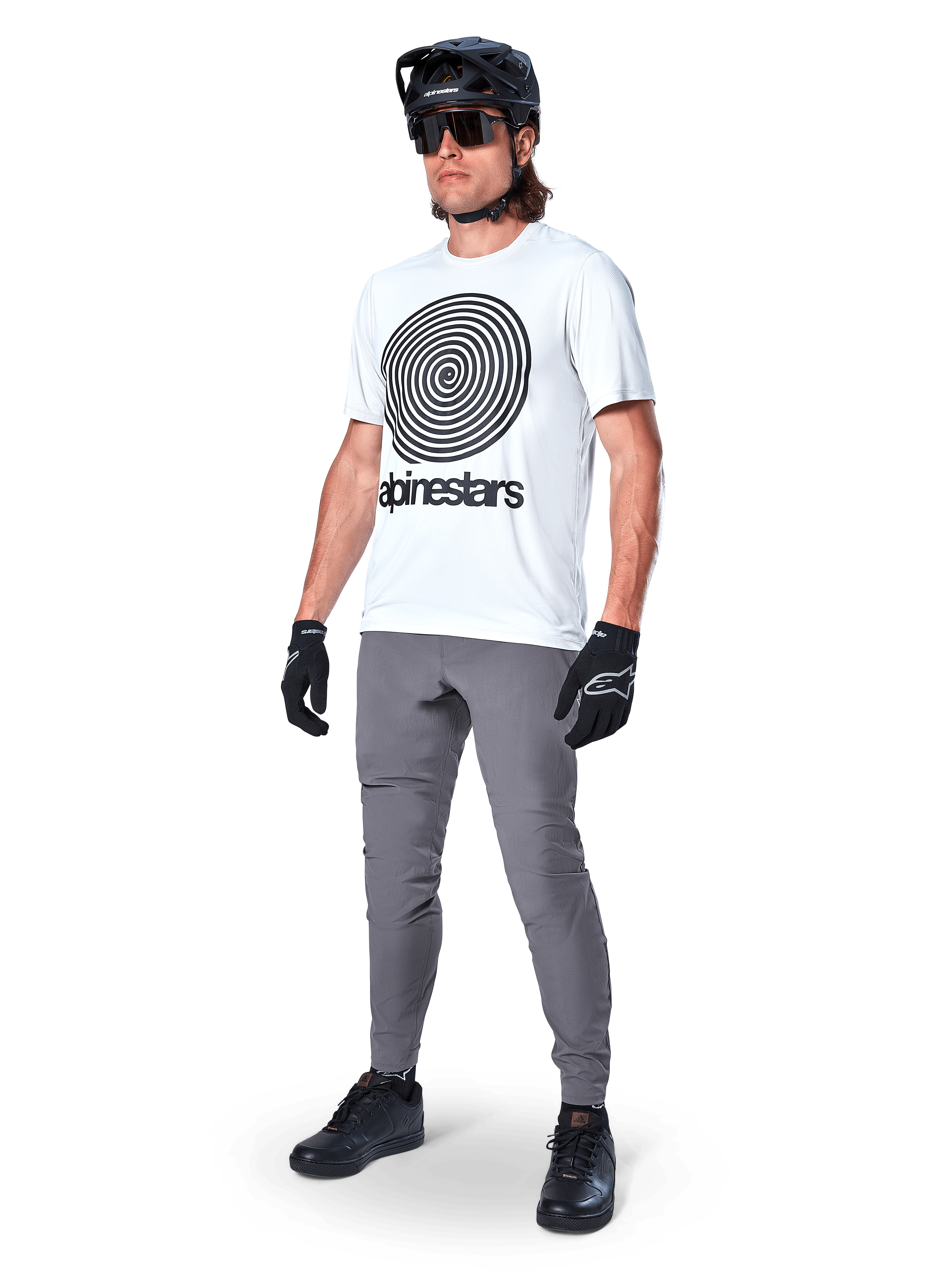Alpinestars A-Dura Oscar Kurzarmtrikot, White Dove mit großer schwarzer Spiralgrafik, getragen von einem Fahrer mit grauer MTB-Hose, schwarzem Helm und Handschuhen, Performance-Radbekleidung für Geländefahrten