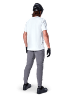 Alpinestars A-Dura Oscar Kurzarmtrikot in White Dove, Rückansicht, getragen von einem Fahrer mit grauer Radhose, schwarzem Helm und Handschuhen, technische Mountainbike-Bekleidung für Offroad-Trailfahrten
