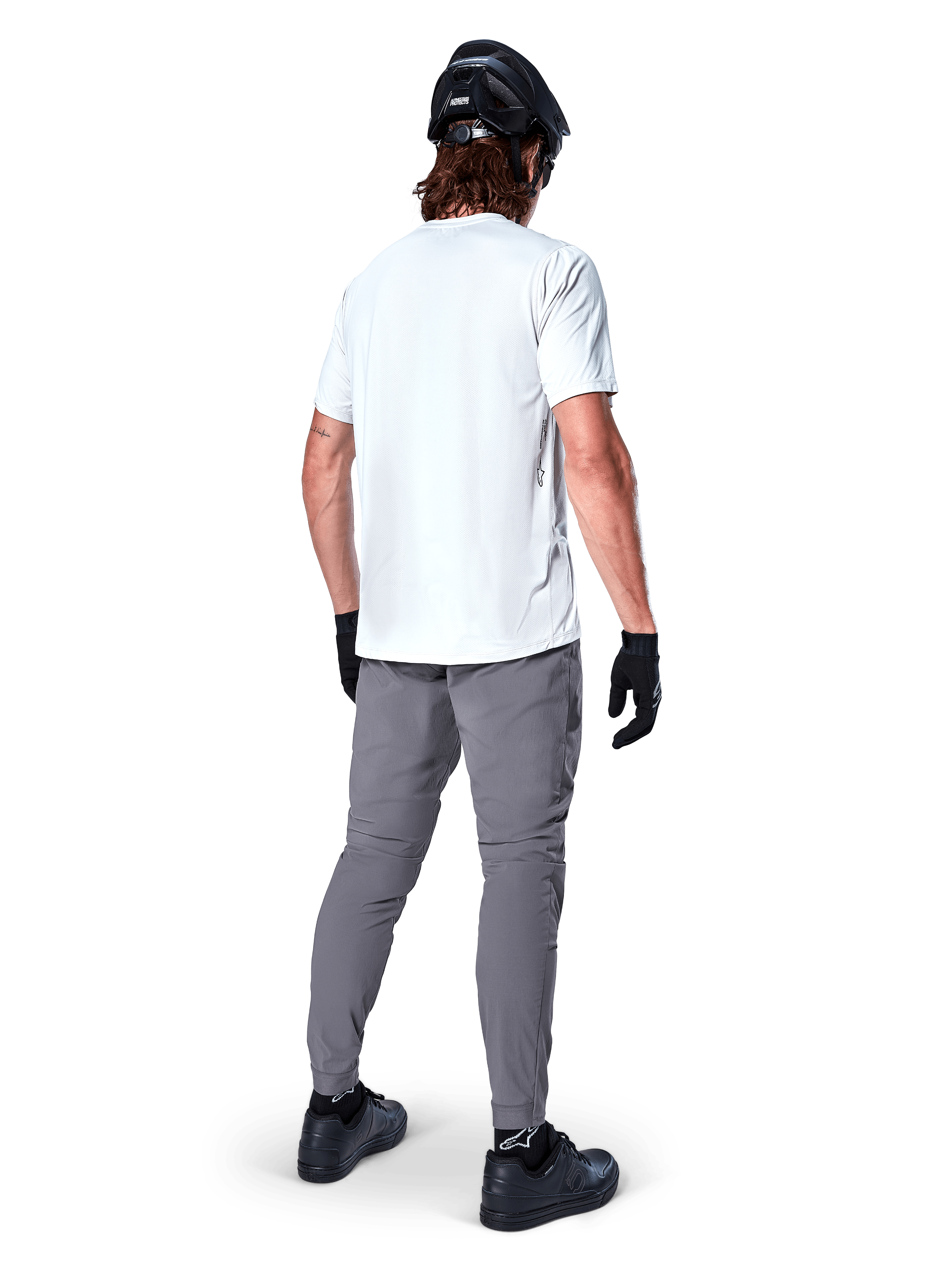 Alpinestars A-Dura Oscar Kurzarmtrikot in White Dove, Rückansicht, getragen von einem Fahrer mit grauer Radhose, schwarzem Helm und Handschuhen, technische Mountainbike-Bekleidung für Offroad-Trailfahrten