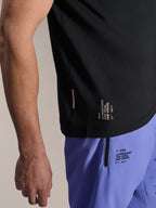 Alpinestars A-Aria Switch Kurzarmtrikot, schwarzes MTB-Trikot, Nahaufnahme des seitlichen Saums mit weißem „ONE GOAL. ONE VISION.“ Branding, getragen mit helllilanen Radshorts mit passenden Logos