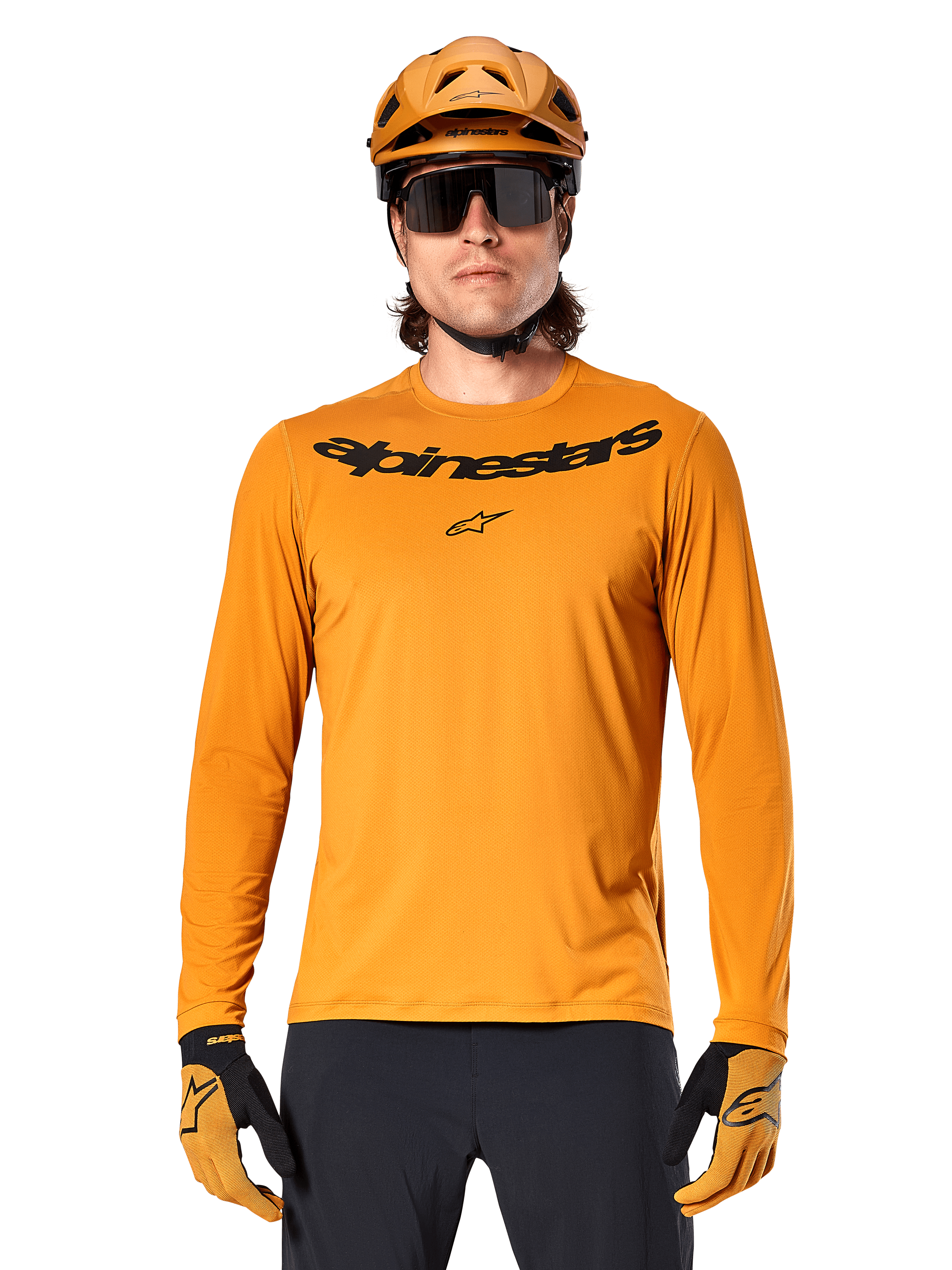 Alpinestars A-Dura Rocker Langarmtrikot in Dunkelgold, mit schwarzem Wortmarken-Logo auf der Brust, getragen mit einem passenden goldenen Helm und Handschuhen für Mountainbike-Performance.