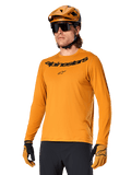 Alpinestars A-Dura Rocker Langarmtrikot, MTB-Mountainbike-Trikot, Dunkelgold, Person trägt Trikot mit passendem Helm und Handschuhen, sportlich abgestimmter Look mit Alpinestars-Wortmarke auf der Brust