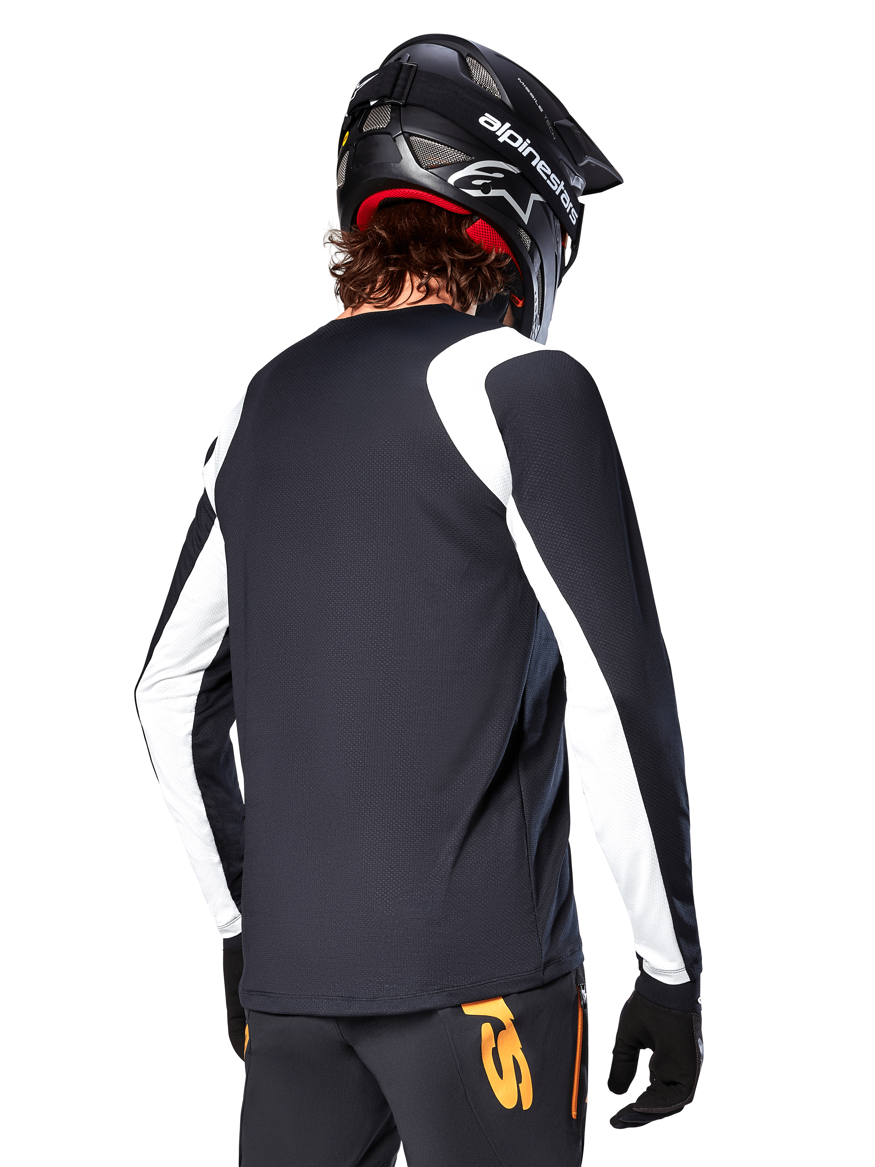 MTB rider wearing Alpinestars A-Supra Oscar Long Sleeve Jersey, Black with white panels on the shoulders and sleeves, viewed from behind, black helmet and gloves, pants with orange accents, durable off-road cycling apparel