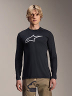 Alpinestars A-Dura Astar Langarm-Jersey, Schwarz mit silbernem Astars-Logo auf der Brust, getragen von einem Modell mit Camouflage-Hose, lässige MTB-Performance-Bekleidung für Mountainbiking