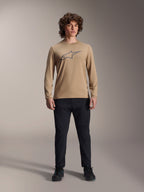 Alpinestars A-Dura Astar Long Sleeve Jersey, Light Brown with grey Astars chest logo, worn by a model with black technical pants and shoes, casual mountain bike performance gear
