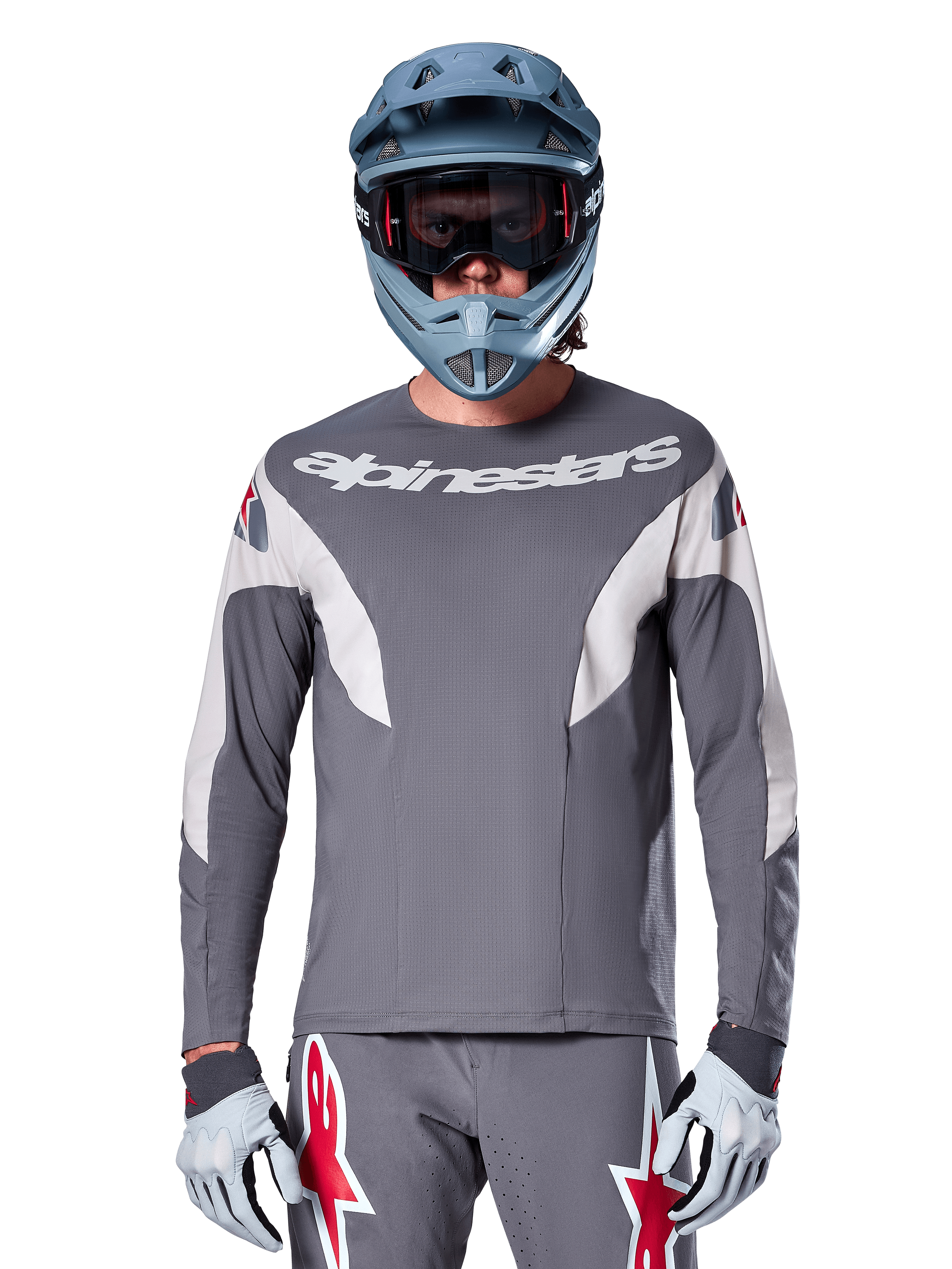 MTB rider wearing Alpinestars A-Supra Race Jersey - Long Sleeve in Dark Gray, long-sleeve cycling jersey with white Alpinestars branding, paired with a blue-gray full-face helmet, goggles, and gray racing gloves, complete mountain bike racing gear for off-road performance