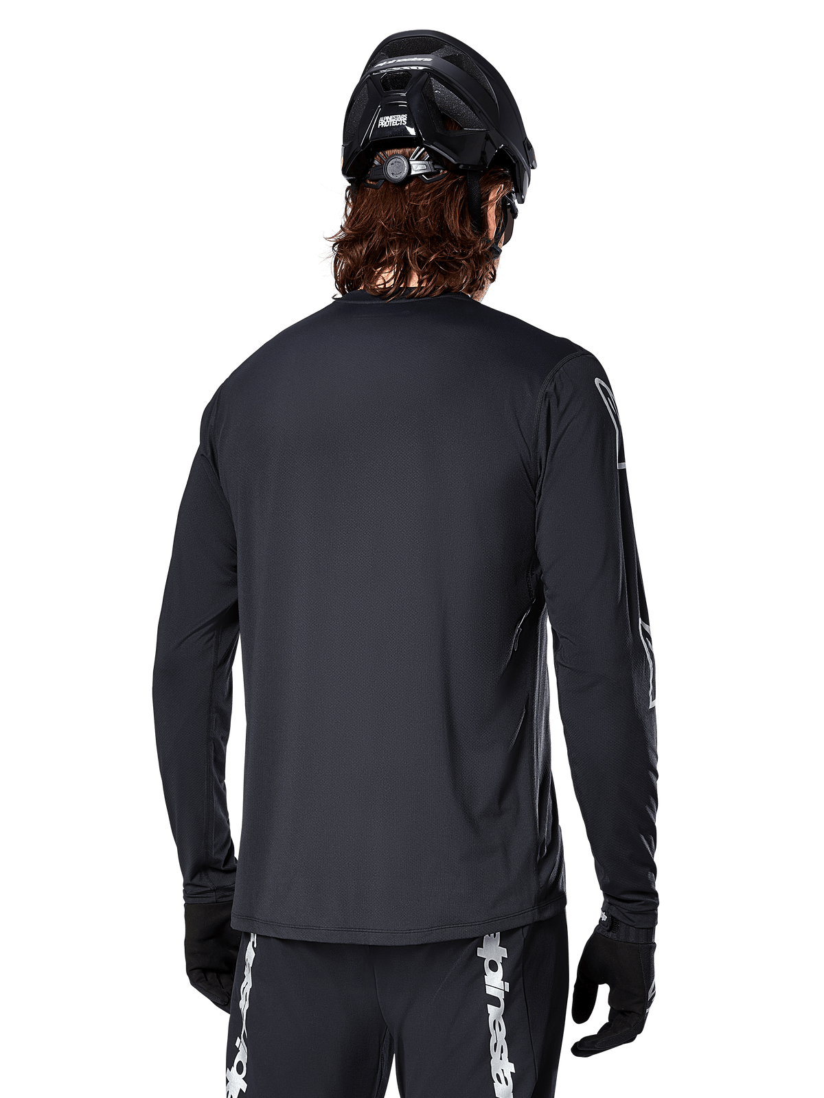 Alpinestars A-Dura Switch Langarmtrikot, Schwarz, Rückansicht eines Radfahrers mit schwarzem MTB-Helm und Handschuhen, mit technischem Jacquard-Gewebe und verlängertem Rückenteil für Offroad-Fahrten