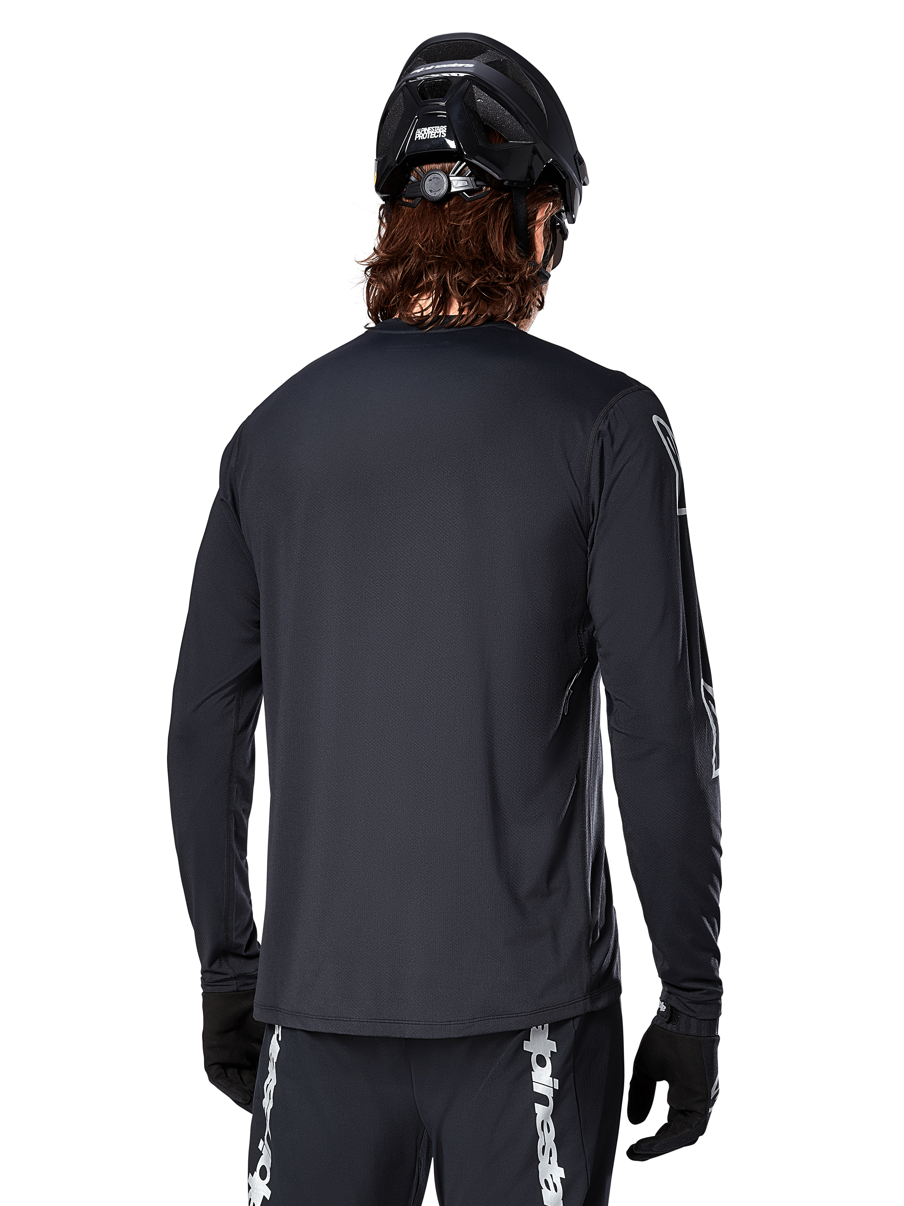 Alpinestars A-Dura Switch Langarmtrikot, Schwarz, Rückansicht eines Radfahrers mit schwarzem MTB-Helm und Handschuhen, mit technischem Jacquard-Gewebe und verlängertem Rückenteil für Offroad-Fahrten