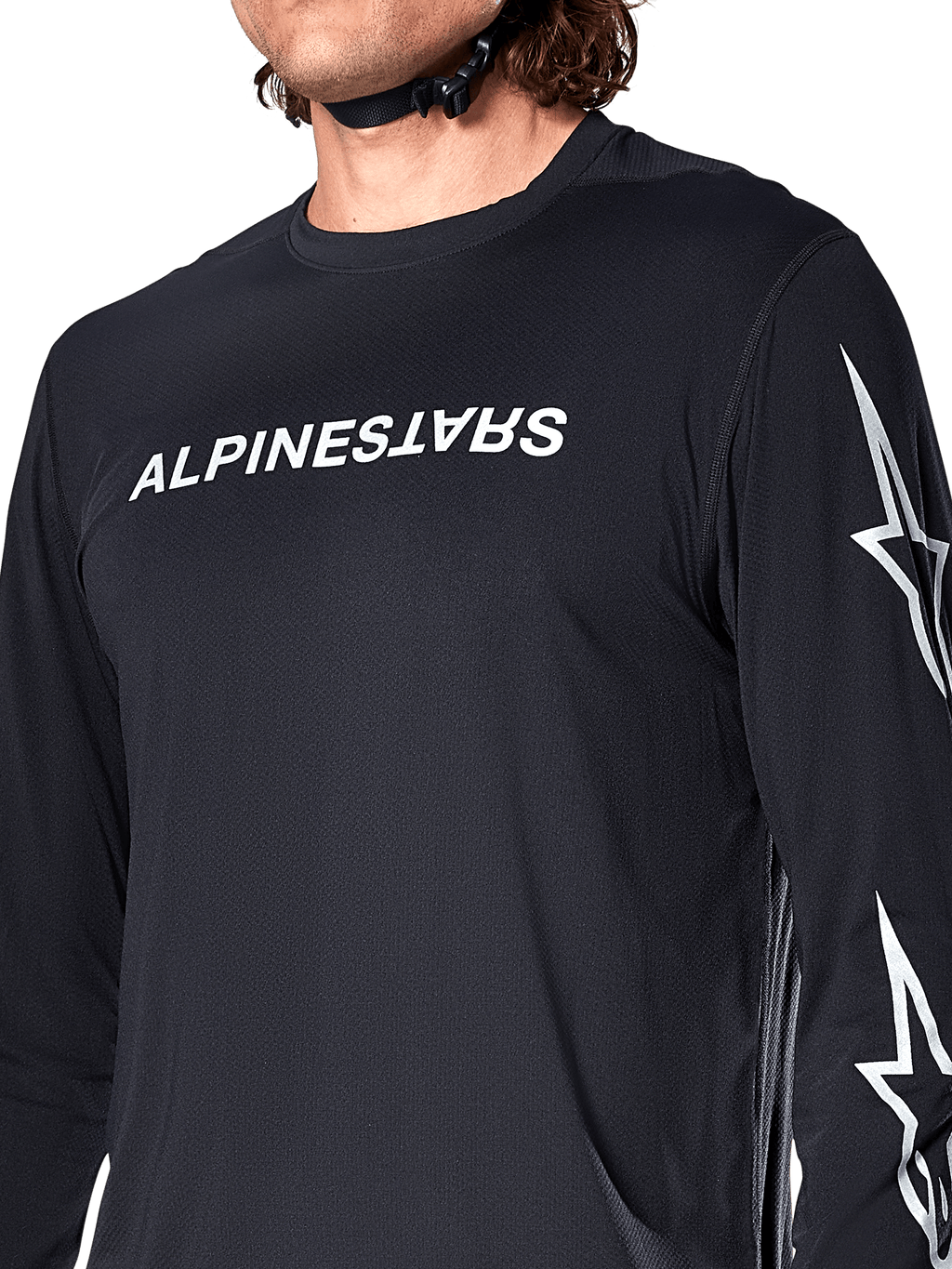 Alpinestars A-Dura Switch Langarmtrikot, Schwarz, mit weißem Alpinestars-Schriftzug auf der Brust und Sternenlogos auf dem Ärmel, getragen von einem Fahrer mit sichtbarem Helmriemen, funktionelle Mountainbike-Bekleidung