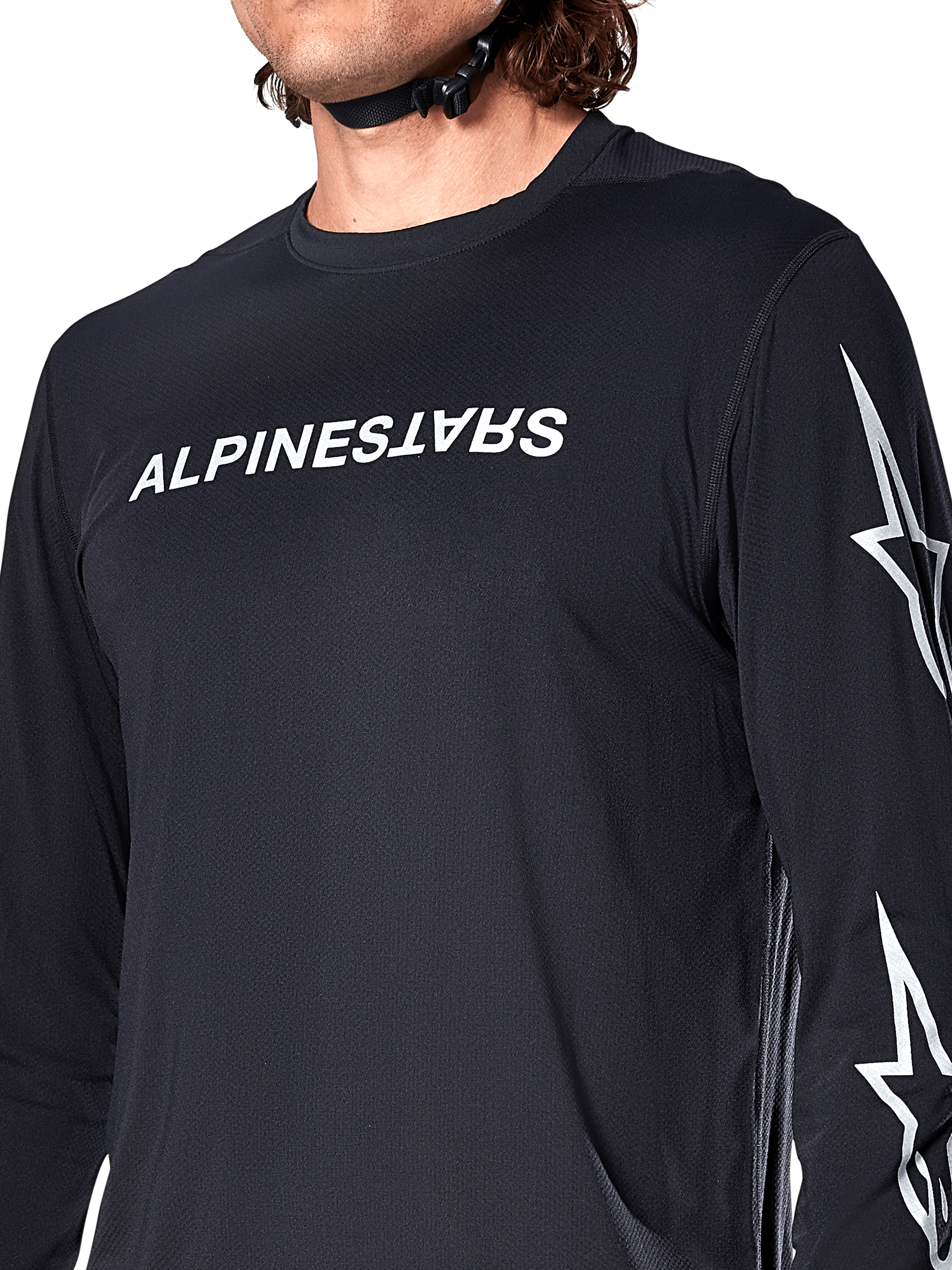 Alpinestars A-Dura Switch Langarmtrikot, Schwarz, mit weißem Alpinestars-Schriftzug auf der Brust und Sternenlogos auf dem Ärmel, getragen von einem Fahrer mit sichtbarem Helmriemen, funktionelle Mountainbike-Bekleidung