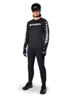 Alpinestars A-Dura Dri Oscar Long Sleeve Jersey, Black Reflective, featuring bold white Alpinestars wordmark on chest and reflective graphic patterns on the sleeves, worn with black mountain bike pants, helmet, and gloves, technical MTB apparel