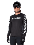 Alpinestars A-Dura Dri Oscar Long Sleeve Jersey, MTB Cycling Jersey, Black Reflective, featuring a white chest wordmark and bold reflective circular graphics on the sleeves, worn with a black helmet and sunglasses, technical moisture-wicking apparel for off-road mountain biking