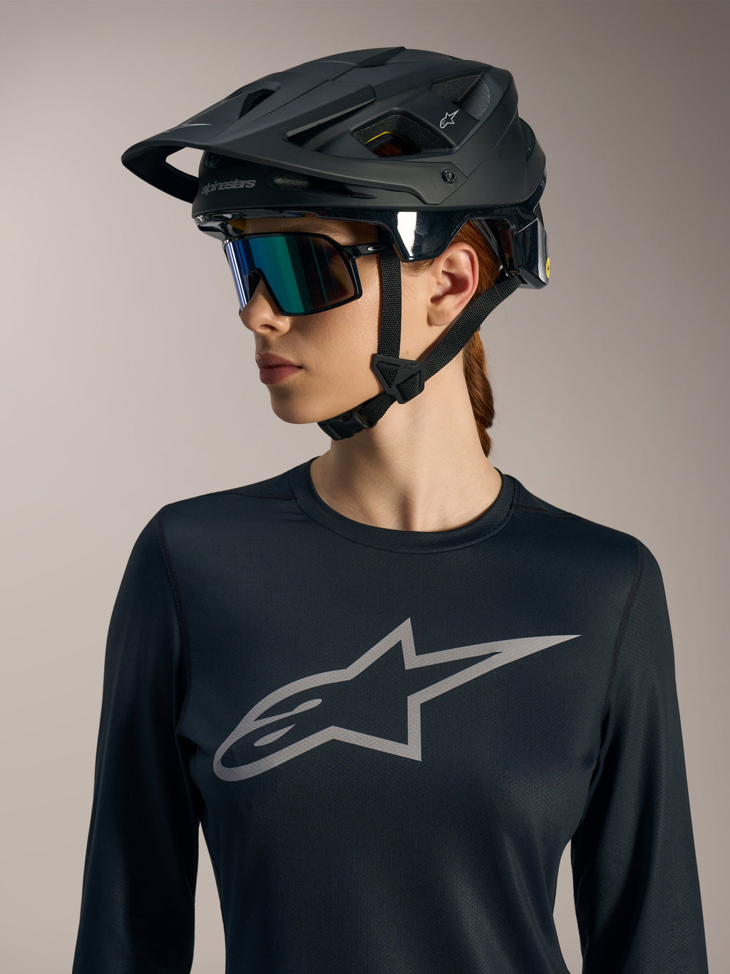 Schwarzes Stella A-Dura Ride Damen-Langarmtrikot mit grauem Astars-Logo und mattem schwarzem MTB-Helm.