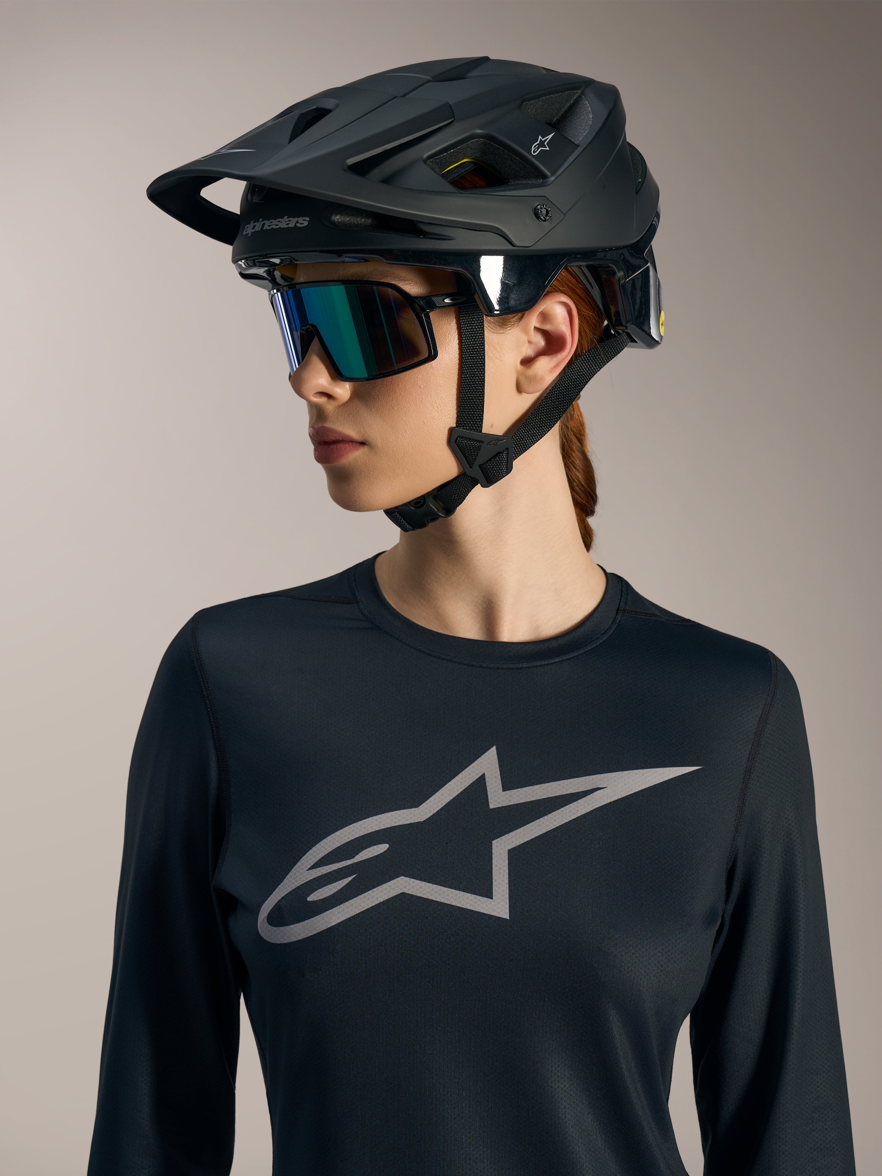 Schwarzes Stella A-Dura Ride Damen-Langarmtrikot mit grauem Astars-Logo und mattem schwarzem MTB-Helm.