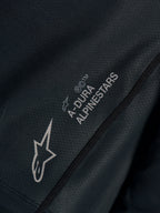 Schwarzes Stella A-Dura Ride Trikot in Nahaufnahme, technisches Jacquard-Gewebe mit A-DURA ALPINESTARS und Astars-Logos.